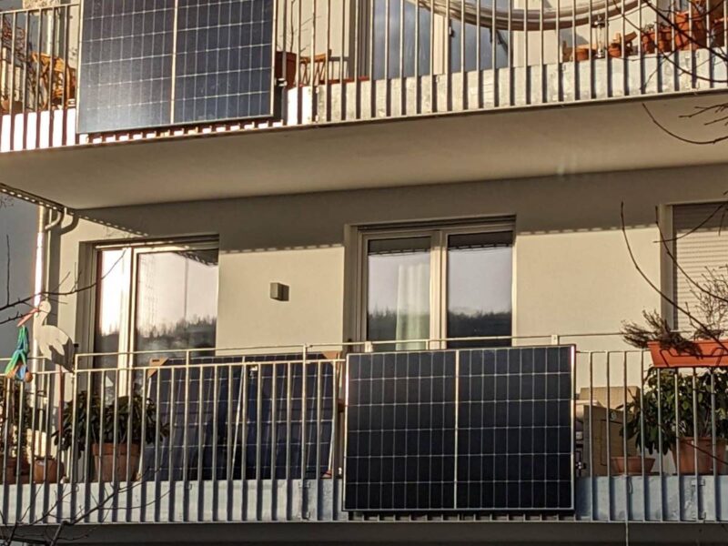 Plug-in solar panels fixed to the metal railings of two balconies on a block of flats
