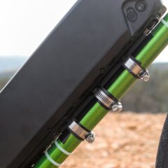 A black e-bike battery pack fixed to the green frame of a bicycle