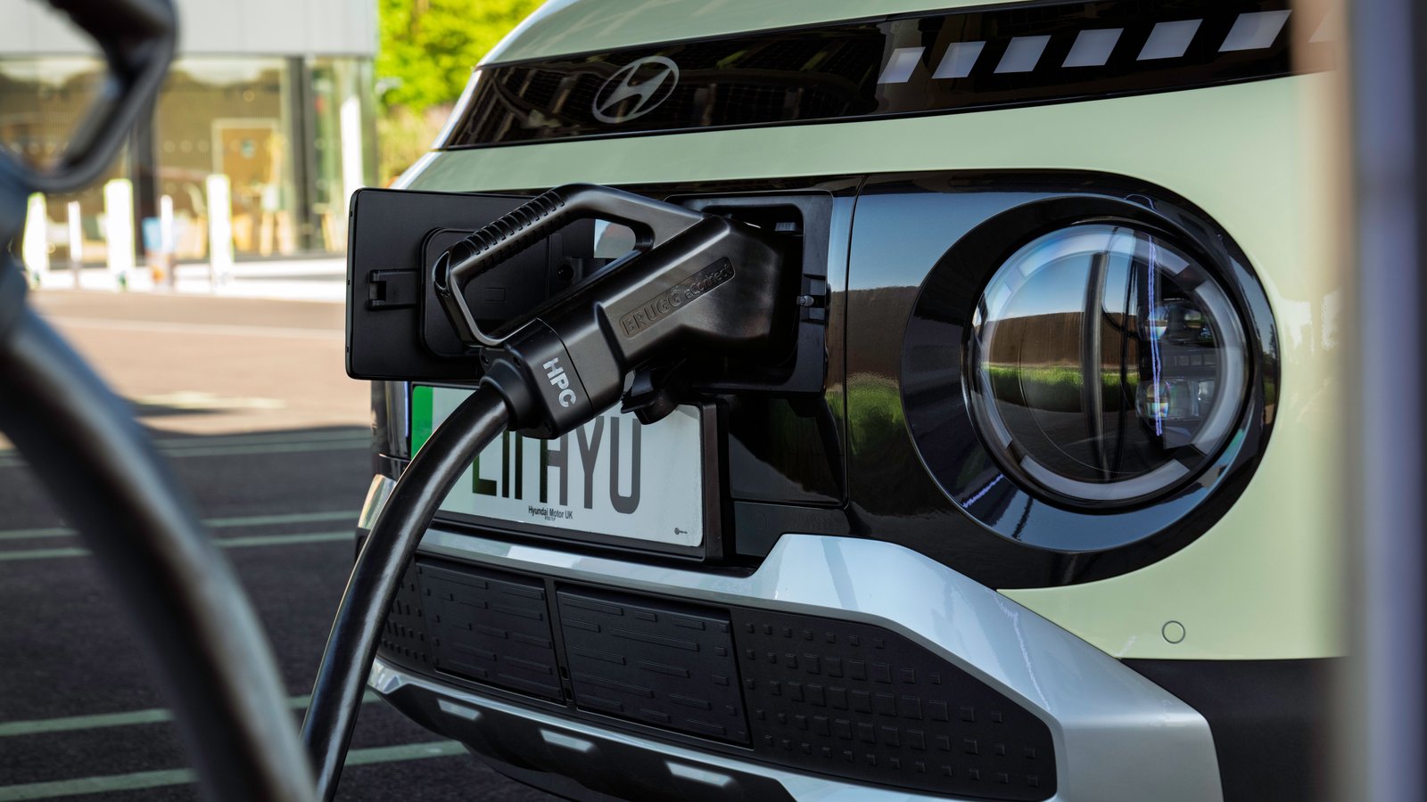 A charging cable plugged into the front charge port of a small electric car