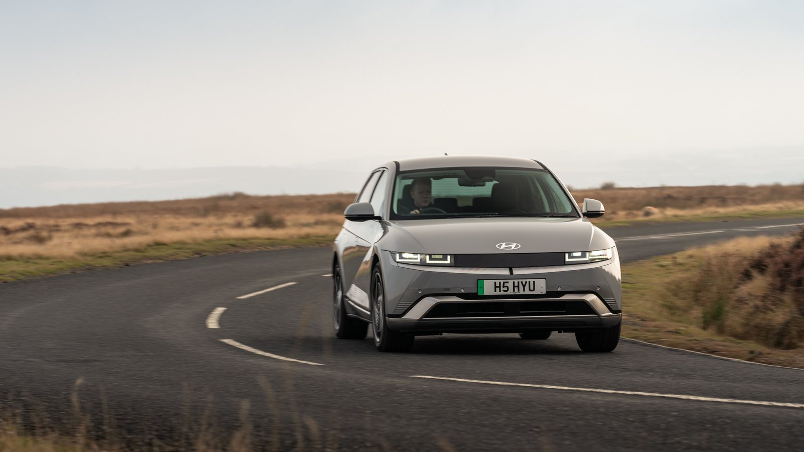 A silver Hyundai IONIQ 5 driving on a winding moorland road