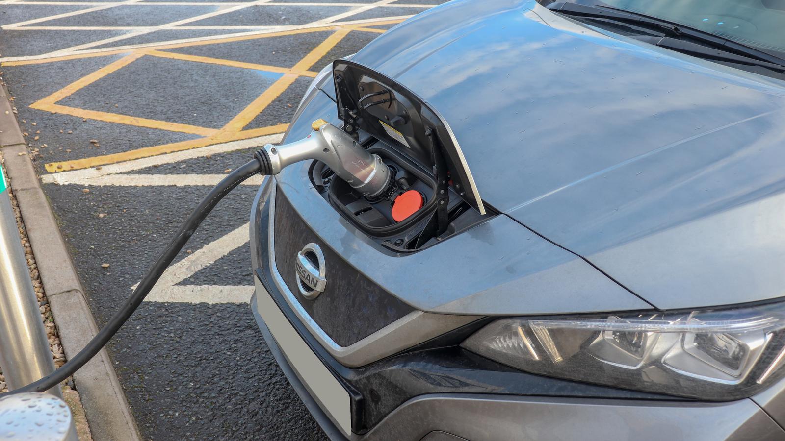A grey Nissan Leaf electric car plugged in at a charging point in a UK car park