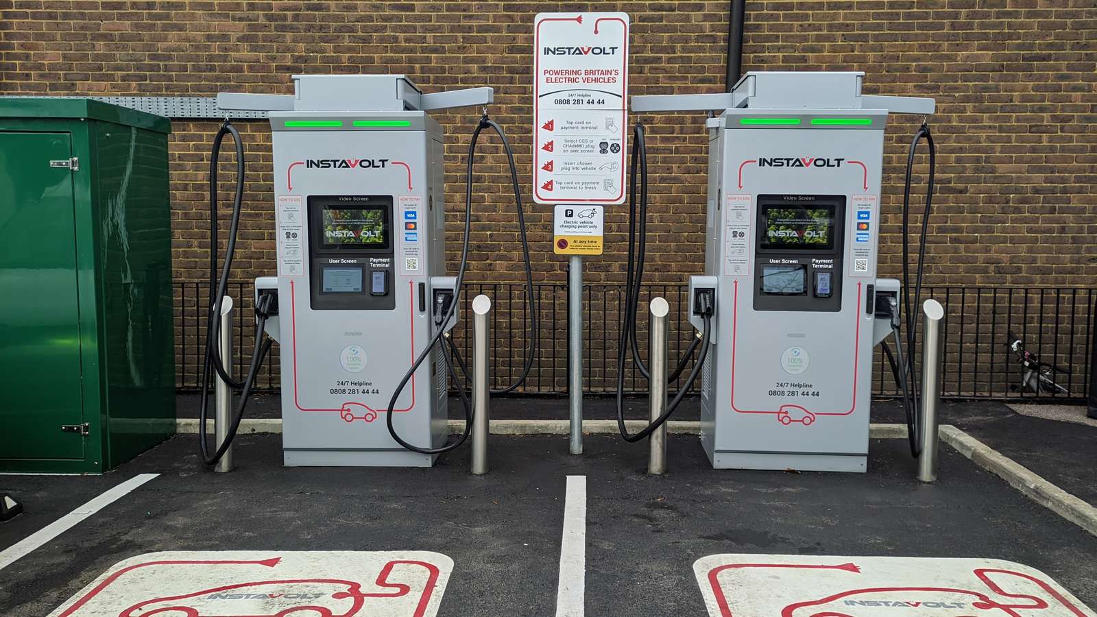 Two public rapid chargers in marked bays in a UK retail car park