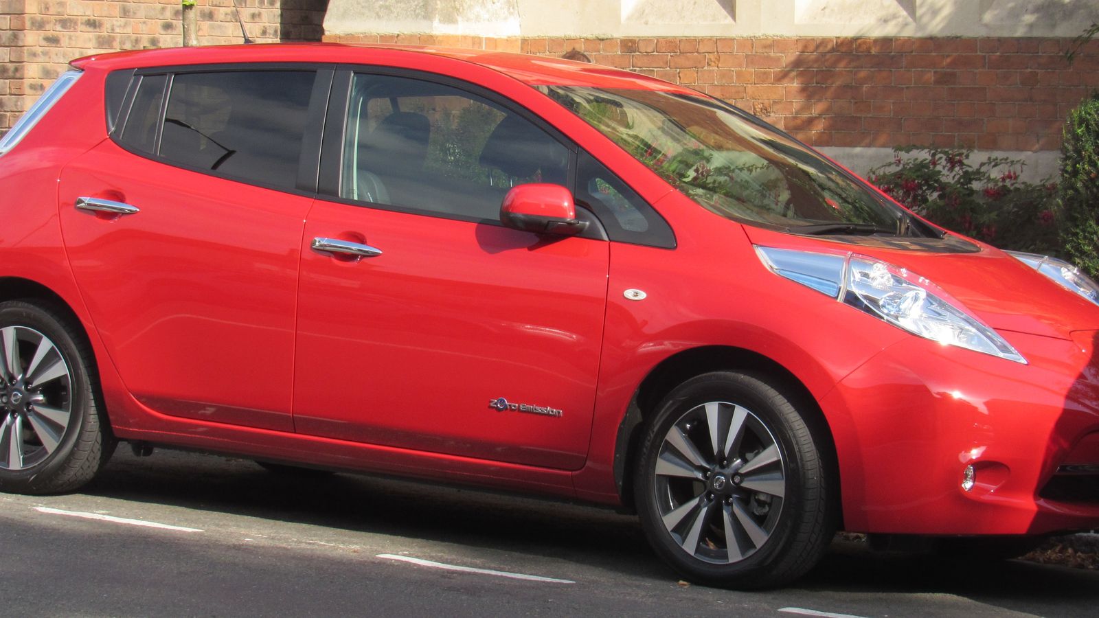 A red 2017 Nissan Leaf electric hatchback parked on a UK street